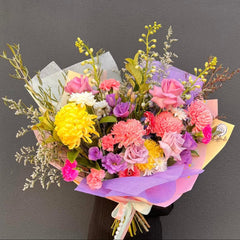 Bouquet of colorful flowers with pink, yellow, and purple tones on a dark background