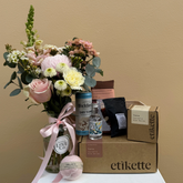 Gift set with flowers, a bottle, and a box labeled 'etikette' on a beige background