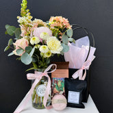 Bouquet of flowers with a jar, bath bomb, and gift bag on a dark background