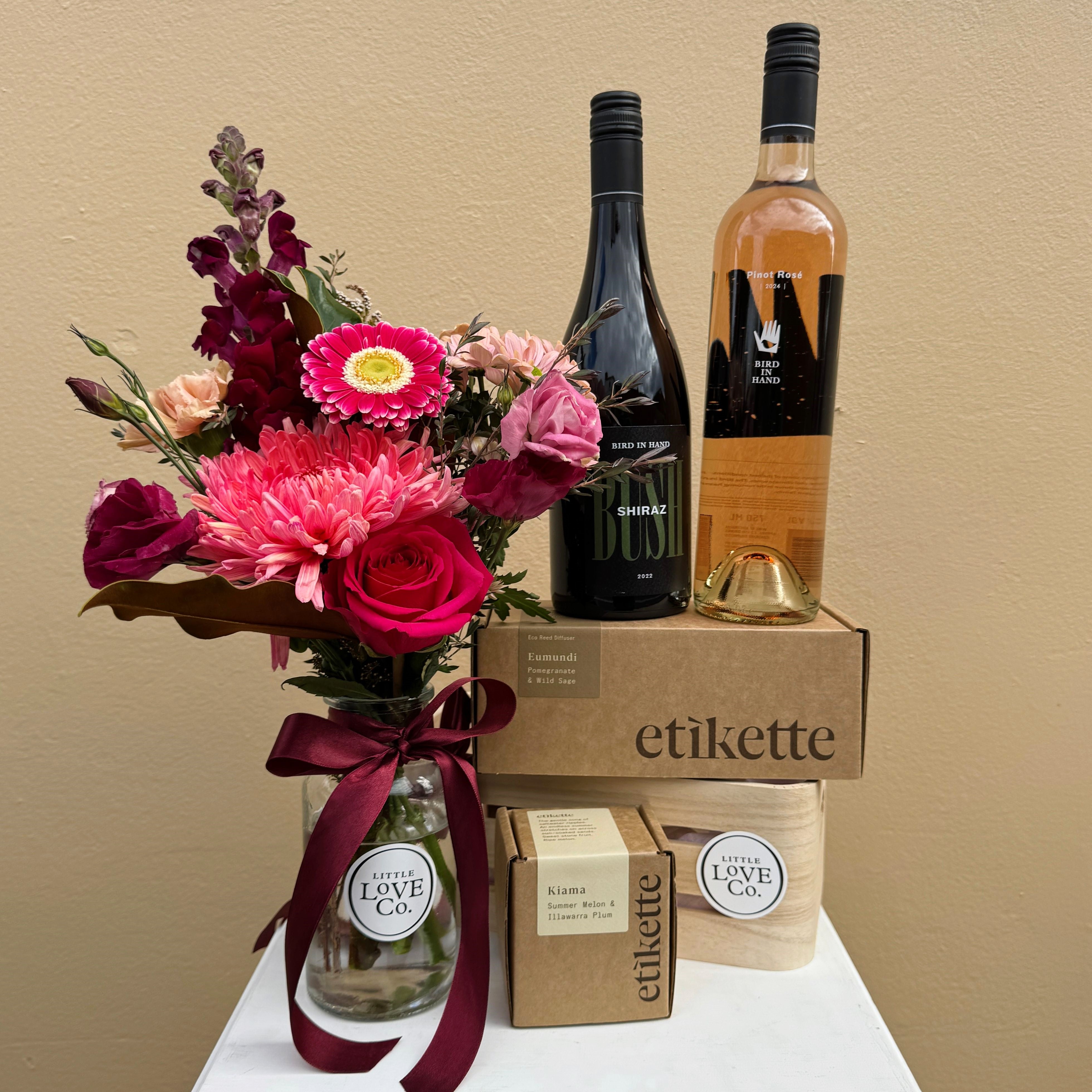 Bouquet of flowers, two bottles of wine, and a box with 'etikette' branding on a beige background.