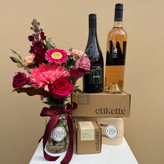 Bouquet of flowers, two bottles of wine, and a box with 'etikette' branding on a beige background.