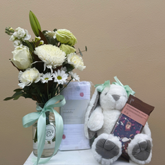 Bouquet of white flowers, plush toy, and gift box on a beige background